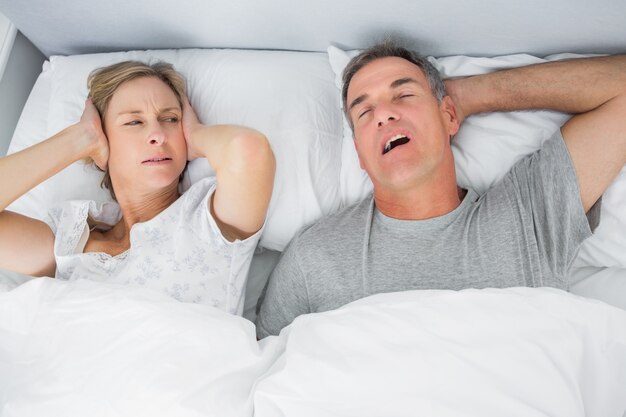 woman is being disturbed by mans' snoring