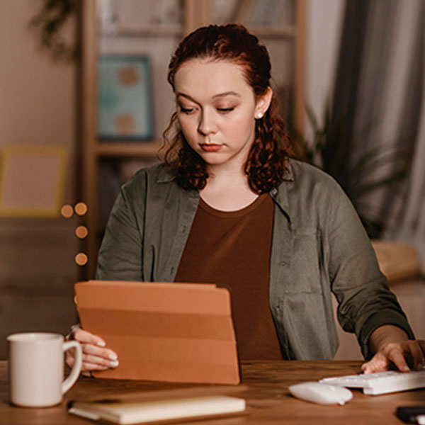 Woman using her tablet at home while having coffee