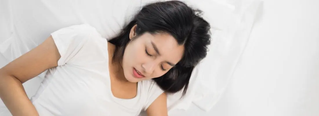 female sleeping on bed with period insomnia pain